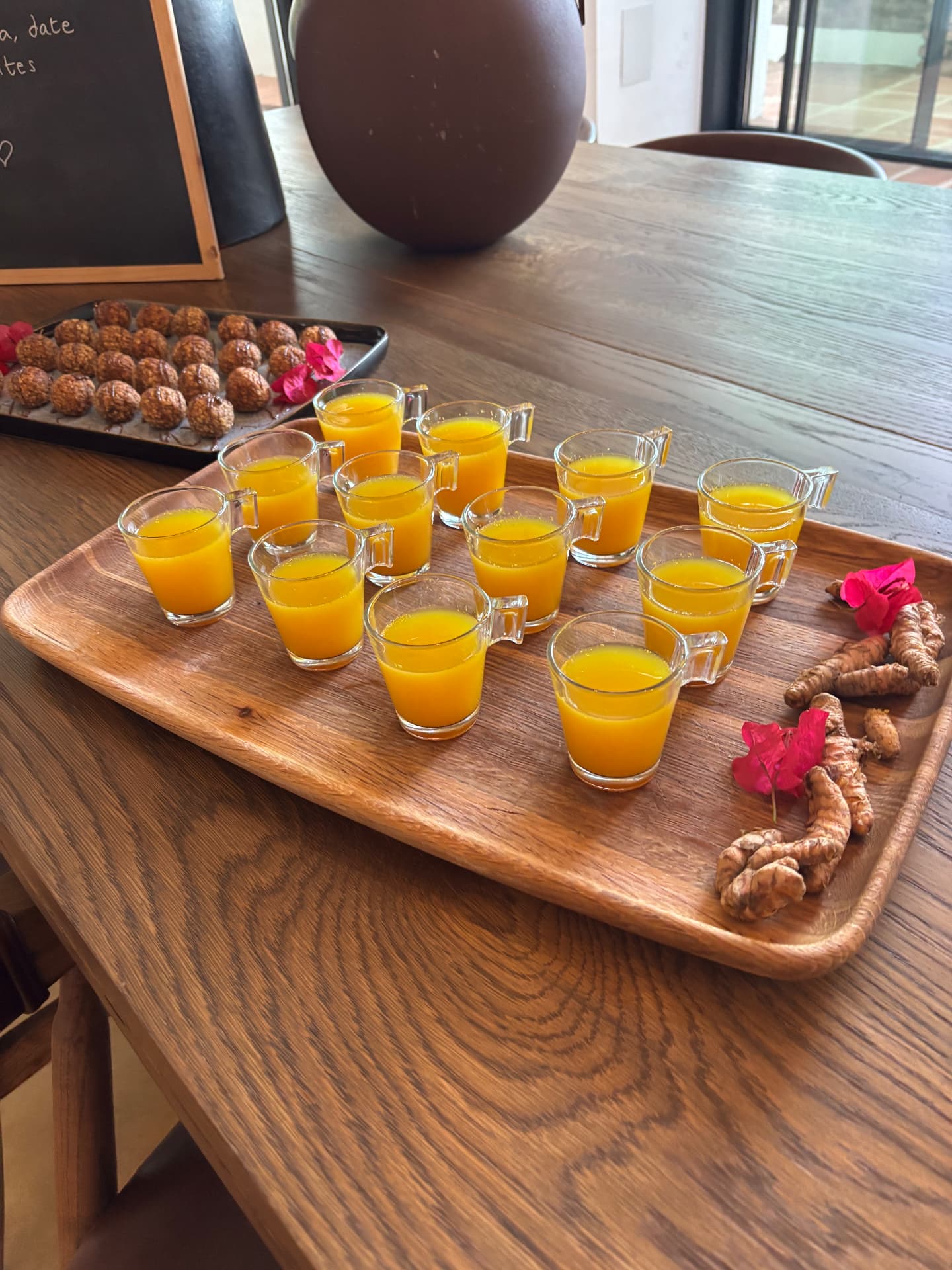 Golden morning drinks and bite-sized snacks arranged on wooden trays with flowers